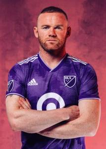 roney de brazos cruzados fondo de humo y playera morada